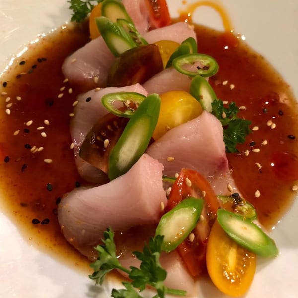 Bonsai Thai & Sushi's Hamachi Carpaccio, featuring thinly sliced fish, colorful tomatoes, and green peppers in sauce.